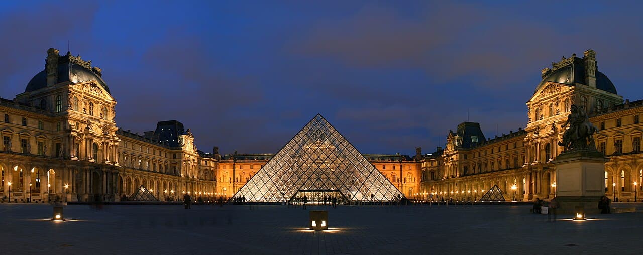 The Louvre Museum glass pyramid illuminated in the Cour Napoléon courtyard in Paris